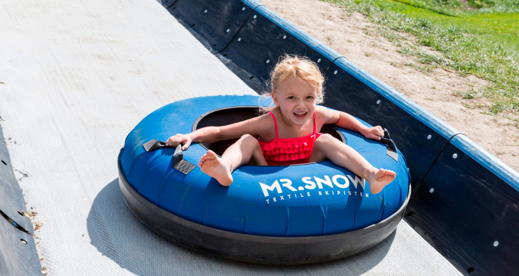 Das Foto zeigt ein junges Mädchen, welches die Tubingbahn runter fährt