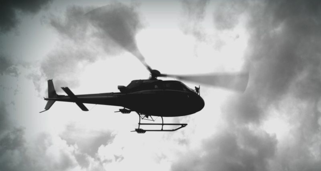Das Foto zeigt ein Helikopter von unten der nah am Boden vorbeifliegt Das Foto zeigt ein Helikopter von unten der nah am Boden vorbeifliegt