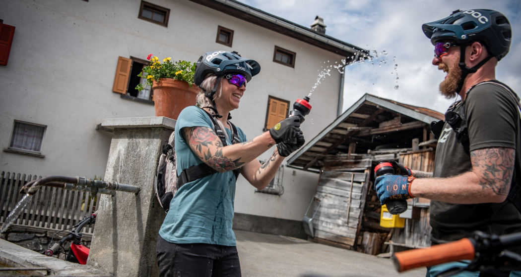 zwei Mountainbiker die eine Pause bei einem Brunnen machen zwei Mountainbiker die eine Pause bei einem Brunnen machen