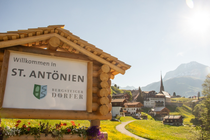 Ortstafel des Bergsteigerdorfes St. Antönien, im Hintergrund das Dorf Ortstafel des Bergsteigerdorfes St. Antönien, im Hintergrund das Dorf