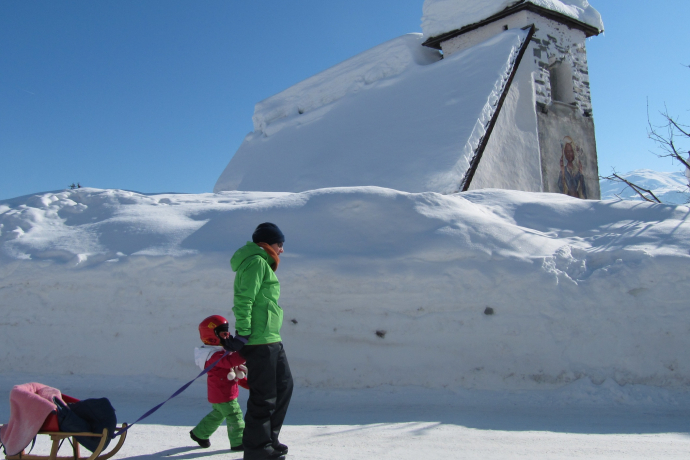 Das Foto zeigt die Kapelle St. Martin im Winter und ein Vater läuft mit ihrer Tochter vor der Kapelle her